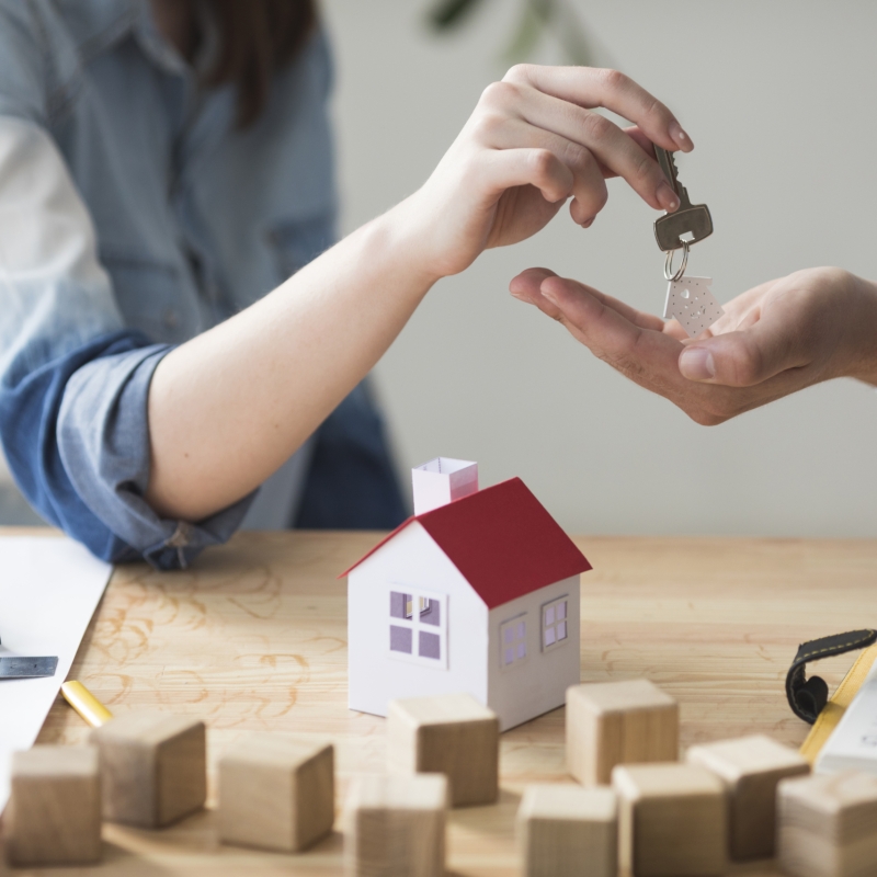 primer-plano-de-la-mano-de-la-mujer-que-da-la-llave-de-la-casa-al-hombre-sobre-mesa-de-madera primer-plano-de-la-mano-de-la-mujer-que-da-la-llave-de-la-casa-al-hombre-sobre-mesa-de-madera